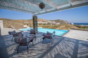 a group of chairs on a patio with a pool at Villa ANAIS 1 MYKONOS in Elia Beach