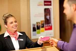 a woman in a suit handing a man a pink card at Mercure Norwich Hotel in Norwich