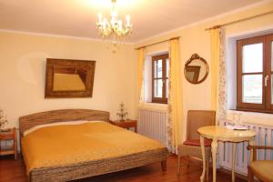 a bedroom with a bed and a table and a chandelier at Seewirt Ecking in Riedering