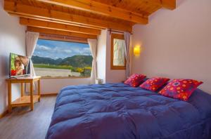 a bedroom with a blue bed and a large window at Cabañas Del Lacar in San Martín de los Andes