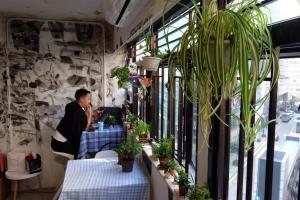 un hombre sentado en una mesa en una habitación con plantas en Hop Inn, en Hong Kong