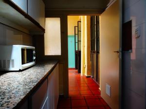 a kitchen with a microwave on a counter and a hallway at Black Sheep International Hostel in Mendoza