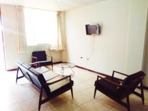sala de estar con 2 sillas y TV en la pared en Aparts Downtown Arequipa, en Arequipa