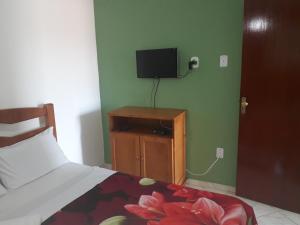 a bedroom with a bed and a tv on a wall at Suítes Xodo Tour in Arraial do Cabo