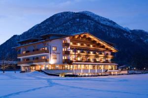 a large building with snow in front of a mountain at Hotel Bergland in Pertisau