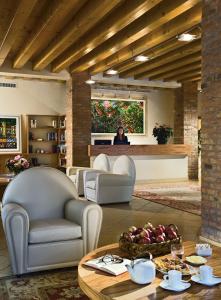 a woman sitting in a living room with a table at Ca' Murà Natura e Resort in Maserà di Padova