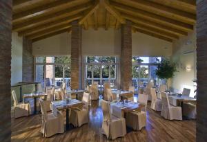 a restaurant with white tables and chairs and windows at Ca' Murà Natura e Resort in Maserà di Padova
