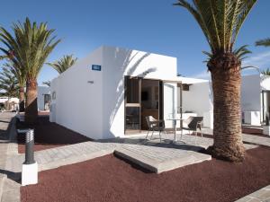 une maison blanche avec des palmiers devant elle dans l'établissement HL Rio Playa Blanca, à Playa Blanca