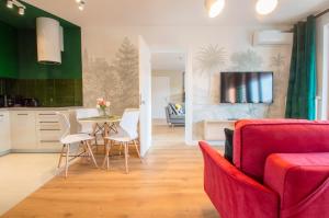 グダニスクにあるGrand Apartments - Apartments SPA Waterlane Islandのリビングルーム(赤いソファ、テーブル、椅子付)