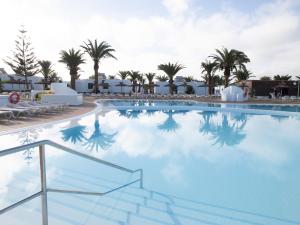 a large swimming pool with palm trees in the background at HL Rio Playa Blanca in Playa Blanca