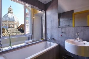 baño con bañera, lavabo y ventana en Palazzetto Rosso - Art Hotel en Siena