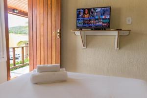 um quarto com uma cama e uma televisão na parede em Pousada Búzios Garden em Búzios