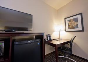 Habitación de hotel con escritorio, TV y mesa con silla. en Cobblestone Inn & Suites - Boone, en Boone