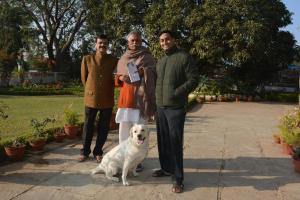 um grupo de três pessoas e um cão branco em Jheelam Homestay em Bhopal