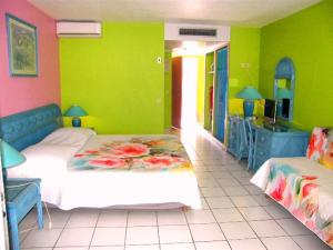 ein Schlafzimmer mit grünen Wänden, einem Bett und einer Küche in der Unterkunft Studio Yucca, Pointe de la verdure, Didier BERVILLE in Le Gosier