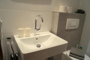 La salle de bains est pourvue d'un lavabo blanc et de toilettes. dans l'établissement Gästehaus Greiter - Sommer Bergbahnen inklusive, à Oberstdorf
