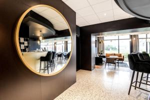 - un miroir rond sur un mur dans une pièce avec des chaises dans l'établissement Brit Hotel Du Stade Rennes Ouest, à Rennes
