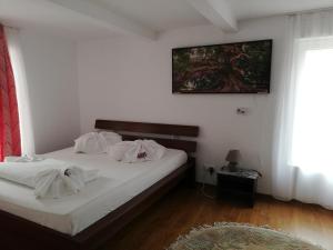 1 dormitorio con 1 cama con sábanas blancas y una foto en la pared en Horia, en Avrig