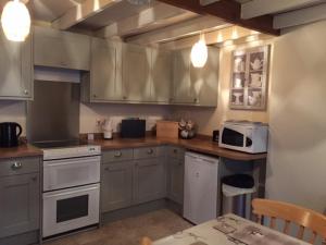 a kitchen with gray cabinets and a white microwave at Lazydays Cottage in Moffat