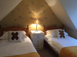 a attic bedroom with two beds and a lamp at Lazydays Cottage in Moffat