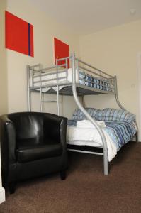 a room with a bunk bed with a black leather chair at The Hostel in Edinburgh