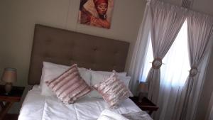 Schlafzimmer mit einem Bett mit weißer Bettwäsche und Kissen in der Unterkunft Tehilah in Sabie