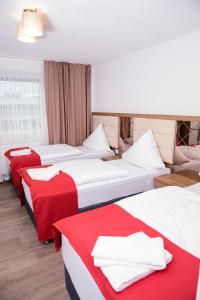 a hotel room with three beds with red and white sheets at Hotel Hausen Obertshausen Frankfurt in Obertshausen