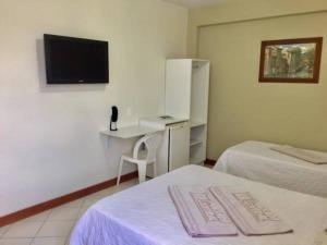 a room with two beds and a desk and a tv at Pousada Central in Feira de Santana +26 photos
