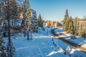 Una calle cubierta de nieve con árboles y una carretera. en Hotel Board, en Jahorina