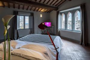 a bedroom with a bed and a desk and windows at Palazzetto Rosso - Art Hotel in Siena
