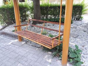 drewniana ławka siedząca pod drzewem w obiekcie Csóka Apartman Pápa w mieście Pápa