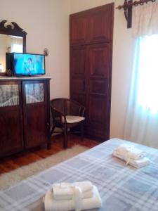 a bedroom with a bed with a television and a chair at Pension Panos in Agios Dimitrios