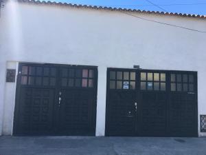 duas portas de garagem pretas num edifício branco em Apartaestudio en Chia em Chía