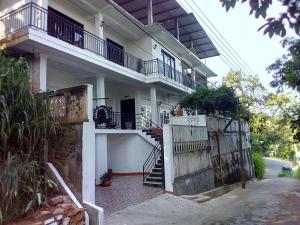 Casa blanca con puerta de madera y escaleras en Kandy Hill Escape, en Kandy