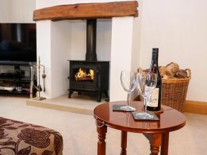 a bottle of wine and two glasses on a table in front of a fireplace at Long Ing Farm in Holmfirth