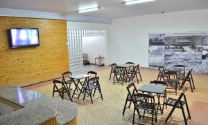 a room with tables and chairs and a tv on a wall at Pousada Central in Feira de Santana