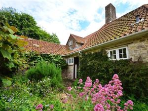 una casa con un jardín con flores delante en Sixpenny Cottage, en Upwey