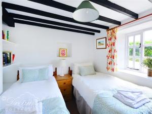 dos camas sentadas una al lado de la otra en un dormitorio en Little Berwick Cottage en Burton Bradstock