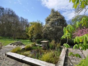 un jardín con un puente de madera, flores y árboles en Sixpenny Cottage, en Upwey