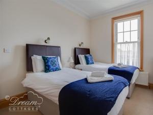 a bedroom with two beds with blue sheets and a window at Beach View Apartment 3 in Weymouth