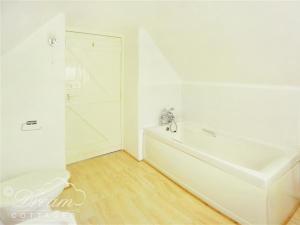 a white bathroom with a white tub and a shower at Little Berwick Cottage in Burton Bradstock