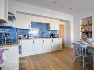 韋茅斯的住宿－Waterside，厨房配有白色橱柜和蓝色瓷砖墙。