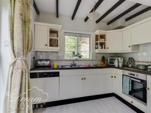 a kitchen with white cabinets and a window at Little Berwick Cottage in Burton Bradstock +15 photos