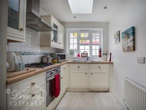 eine Küche mit weißen Schränken und einem Herd mit Backofen in der Unterkunft Ocean Swell in Weymouth