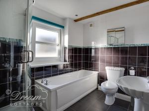 a bathroom with a tub and a toilet and a sink at Ammonite Cottage in Portland +24 photos