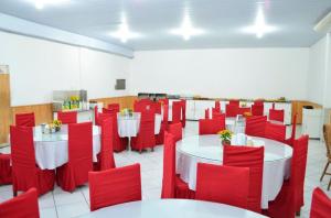 a room with white tables and red chairs at Pousada Central in Feira de Santana