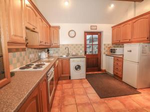 a kitchen with wooden cabinets and a washer and dryer at Piggery Place in Buxton