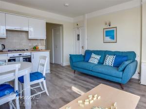 Harbour Edge في ويماوث: غرفة معيشة مع أريكة زرقاء ومطبخ