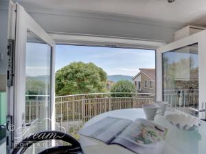 a room with a large window and a table with a book at Bowleaze View in Weymouth