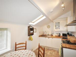 a kitchen with white cabinets and a table in it at Warmwell Lodge in Dorchester